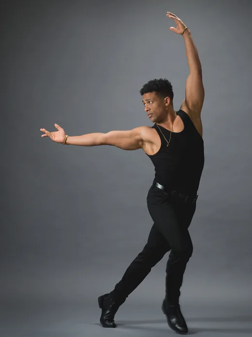 Maikel Mota in a dance pose, one arm stretched upwards
